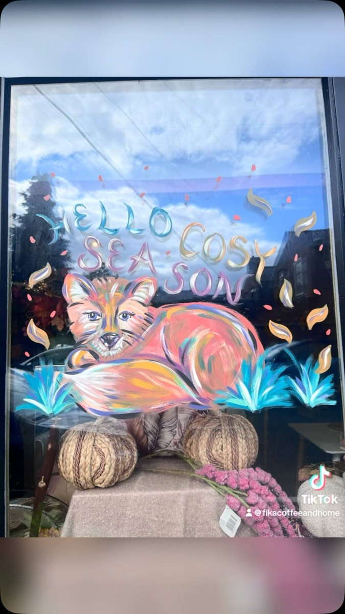 Fika's window painted with a sleeping fox and 'Hello cosy season'
